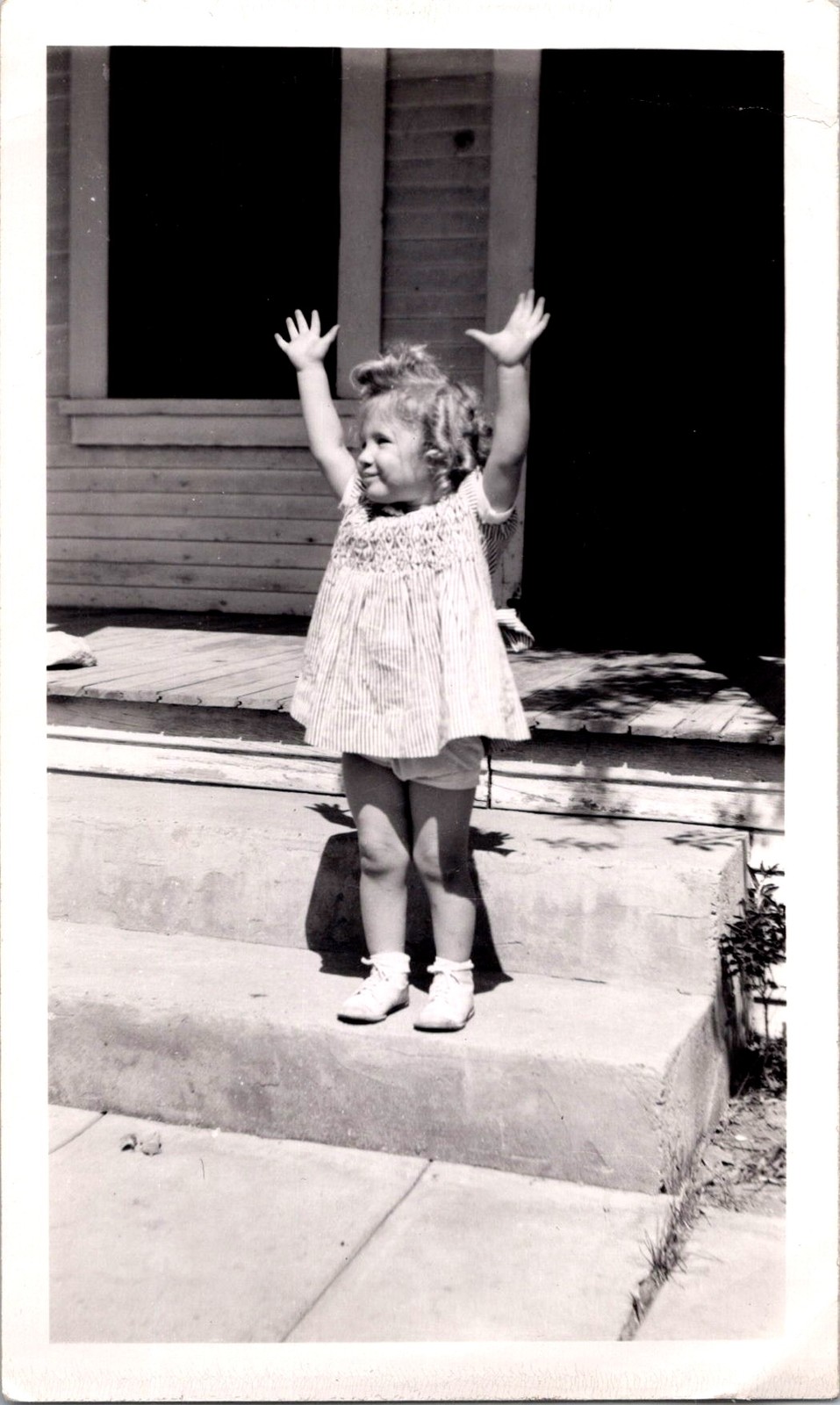 Joyful Toddler Girl with Raised Arms on Porch Steps, 1950s Snapshot Photo