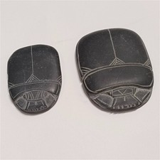 Two black carved stones with geometric patterns, handcrafted scarab design. picture
